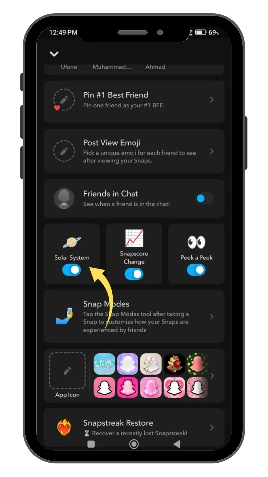 A smartphone screen displaying Snapchat's "Friend Solar System" feature settings. The interface shows options such as "Pin #1 Best Friend," "Post View Emoji," "Friends in Chat," and a highlighted "Solar System" toggle switch turned on. The toggle is marked with a yellow arrow pointing to it. Additional options like "Snapscore Change," "Peek a Peek," and "Snap Modes" are also visible. The screen has a dark mode theme with various colorful app icon choices and a "Snapstreak Restore" option at the bottom.