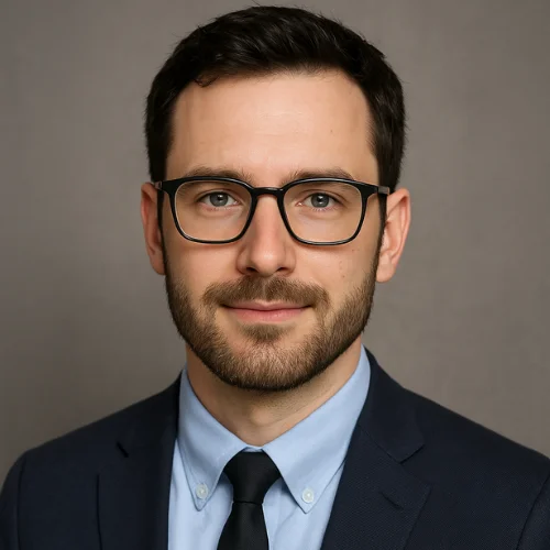 Paul Rainey, author and software engineer, wearing a navy suit and glasses, posing professionally against a neutral gray background.